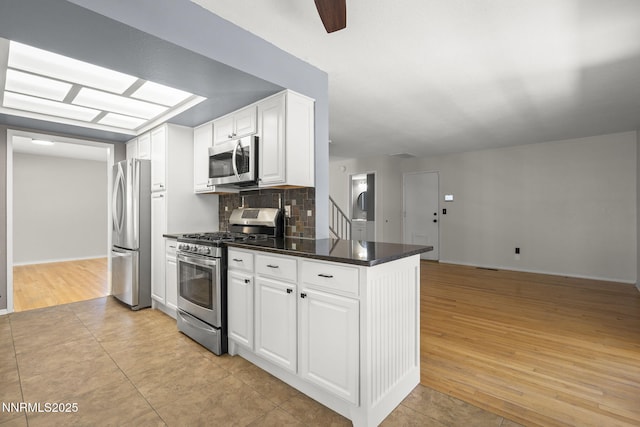 2125 Woodhaven Ln, Sparks, NV 89434 - kitchen featuring stainless steel appliances, dark countertops, white cabinetry, tasteful backsplash, and light tile patterned floors