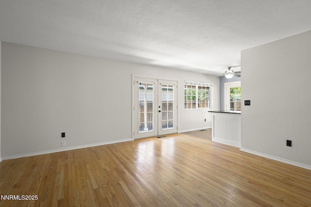 2125 Woodhaven Ln, Sparks, NV 89434 - unfurnished living room featuring french doors, light wood-style flooring, baseboards, a ceiling fan, and a textured ceiling