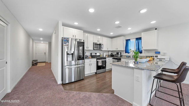 640 Mcgill Dr, Reno, NV 89506 - kitchen with appliances with stainless steel finishes, a peninsula, dark carpet, white cabinets, and light stone countertops
