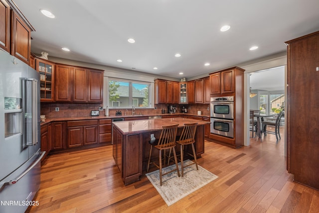 1011 Keystone Ct, Gardnerville, NV 89460 - kitchen featuring appliances with stainless steel finishes, light wood-style flooring, tasteful backsplash, a kitchen bar, and a kitchen island