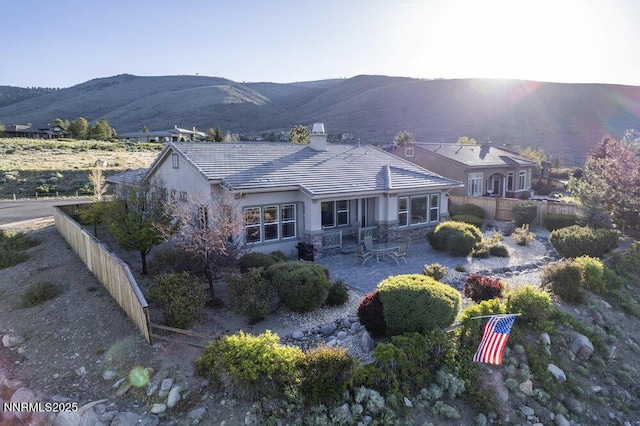10168 Via Fiori, Reno, NV 89511 - back of property featuring a mountain view, a chimney, stucco siding, a patio area, and stone siding