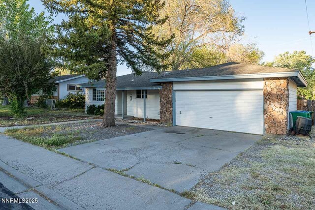 201 N Carson Meadow Dr, Carson City, NV 89701 - ranch-style house with stone siding, an attached garage, driveway, and a shingled roof