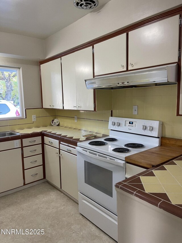 2485 Riviera St, Reno, NV 89509 - kitchen featuring white electric stove, tile countertops, under cabinet range hood, tasteful backsplash, and white cabinets