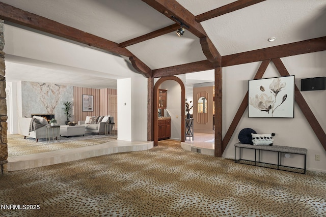 5101 Eldorado Dr, Reno, NV 89519 - unfurnished living room featuring beamed ceiling, carpet, a premium fireplace, arched walkways, and baseboards