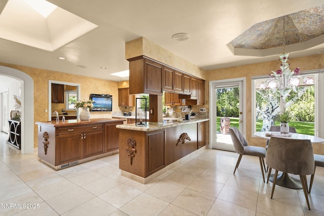 5101 Eldorado Dr, Reno, NV 89519 - kitchen with a peninsula, arched walkways, a sink, light tile patterned floors, and light stone countertops