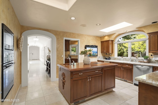 5101 Eldorado Dr, Reno, NV 89519 - kitchen with stainless steel dishwasher, a skylight, oven, light tile patterned floors, and an island with sink