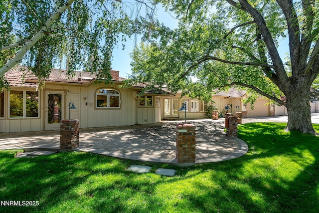 5101 Eldorado Dr, Reno, NV 89519 - back of house with board and batten siding, a patio area, a lawn, and a chimney