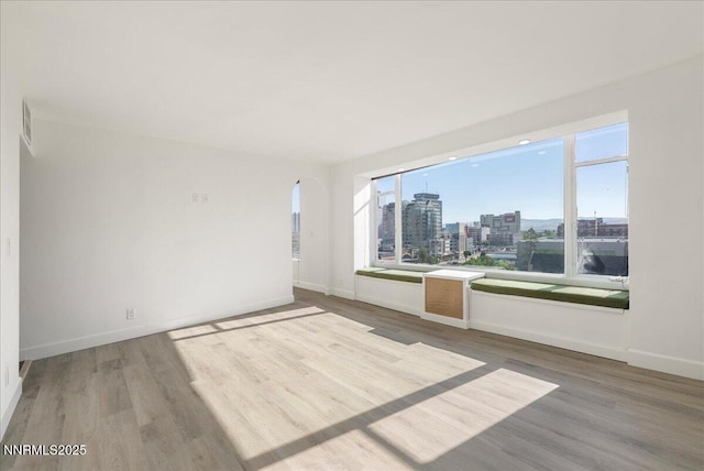 280 Island Ave Apt 906, Reno, NV 89501 - spare room featuring a city view, wood finished floors, arched walkways, and healthy amount of natural light