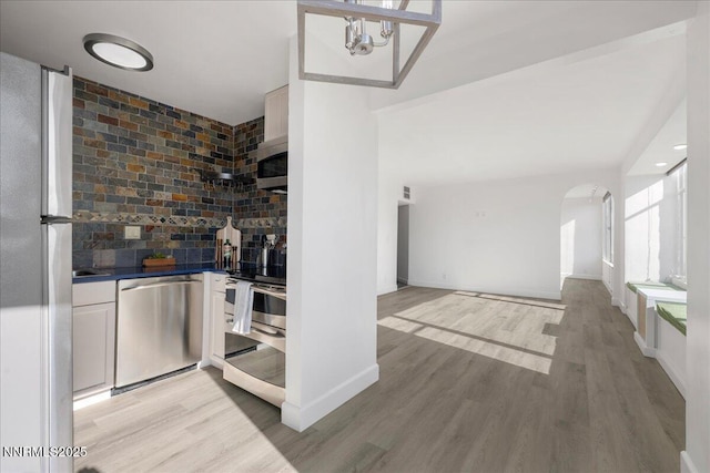 280 Island Ave Apt 906, Reno, NV 89501 - bar area with appliances with stainless steel finishes, light wood-style flooring, arched walkways, and backsplash