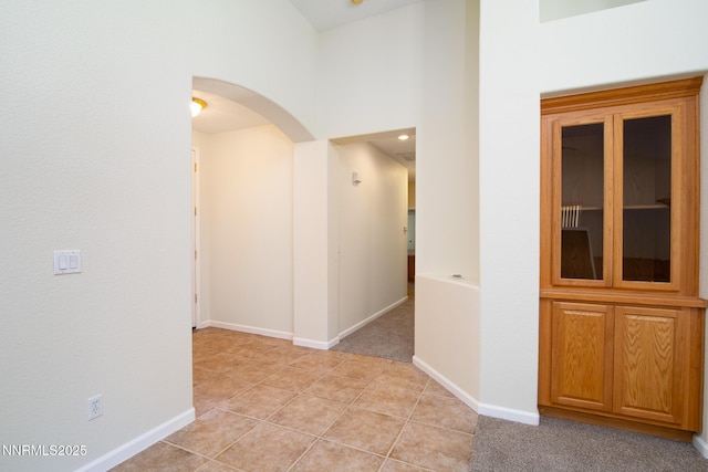 637 Donner Pass Ct, Sparks, NV 89436 - hall with arched walkways, light tile patterned floors, baseboards, a high ceiling, and light colored carpet