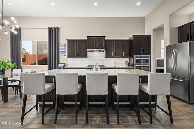 9425 Stony Hill Rd, Reno, NV 89521 - kitchen with stainless steel appliances, tasteful backsplash, a center island with sink, under cabinet range hood, and recessed lighting