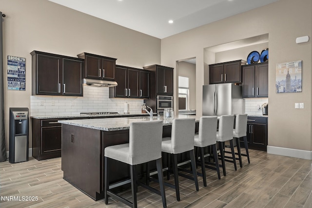 9425 Stony Hill Rd, Reno, NV 89521 - kitchen with appliances with stainless steel finishes, light wood finished floors, a sink, decorative backsplash, and a kitchen bar