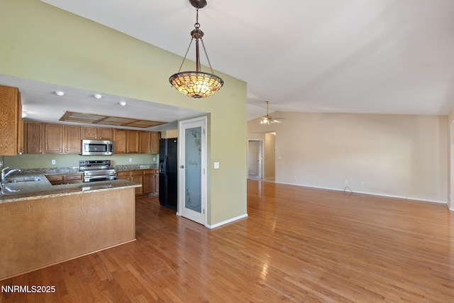 439 Beau Ct, Sparks, NV 89436 - kitchen with appliances with stainless steel finishes, open floor plan, vaulted ceiling, brown cabinetry, and light wood-style flooring