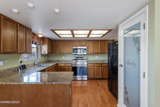 439 Beau Ct, Sparks, NV 89436 - kitchen featuring appliances with stainless steel finishes, a sink, brown cabinets, light wood finished floors, and a peninsula