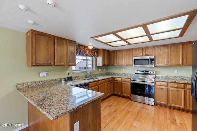 439 Beau Ct, Sparks, NV 89436 - kitchen with stainless steel appliances, brown cabinetry, a peninsula, light wood-type flooring, and a sink