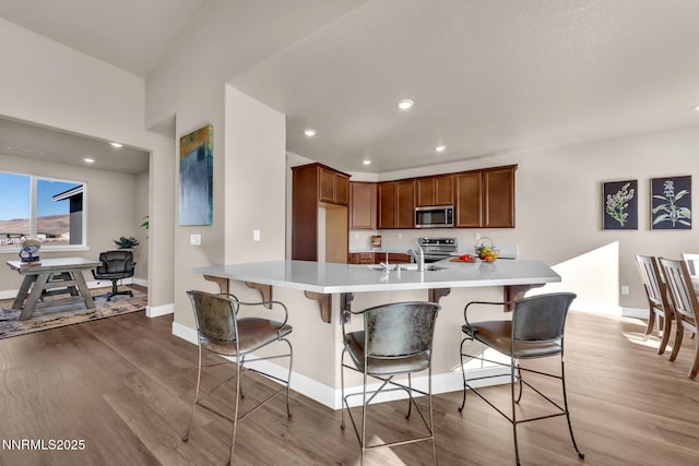 255 Pinto Ranch Ct, Reno, NV 89510 - kitchen featuring stainless steel appliances, light wood-type flooring, baseboards, a kitchen bar, and recessed lighting