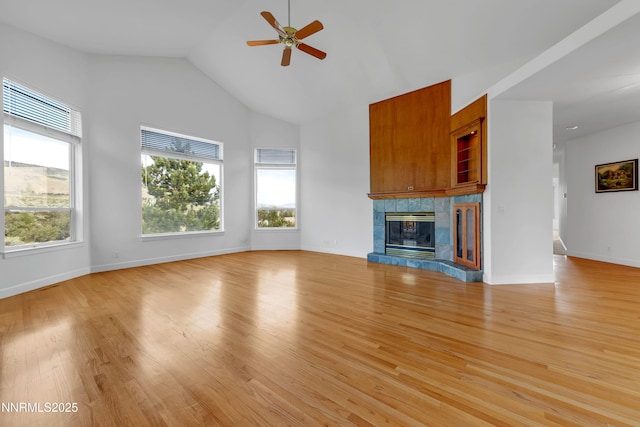 615 Oxbow Ct, Reno, NV 89511 - unfurnished living room with a ceiling fan, a tiled fireplace, light wood finished floors, high vaulted ceiling, and baseboards