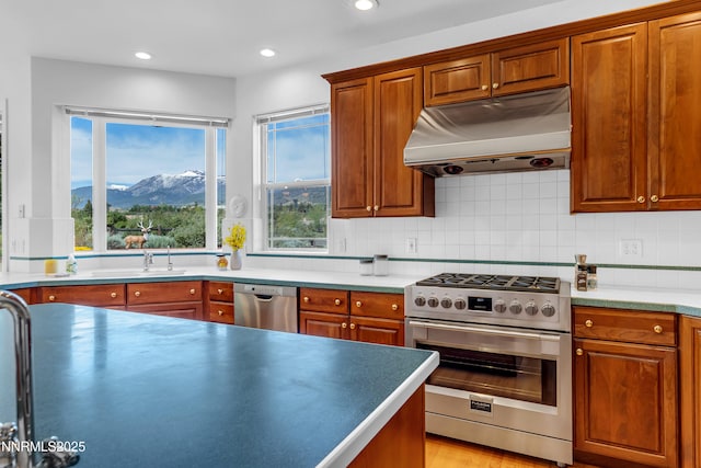 615 Oxbow Ct, Reno, NV 89511 - kitchen with under cabinet range hood, appliances with stainless steel finishes, backsplash, a mountain view, and recessed lighting