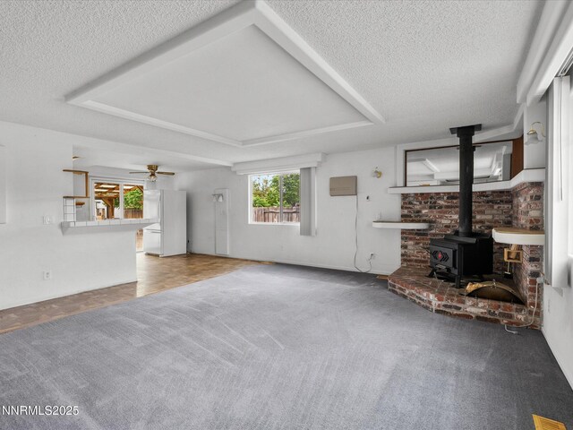 1344 Patricia Dr, Gardnerville, NV 89460 - unfurnished living room with a wood stove, a textured ceiling, carpet, a tray ceiling, and ceiling fan