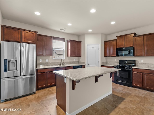 1105 Fiore Ct, Minden, NV 89423 - kitchen featuring black appliances, a sink, a breakfast bar, light stone counters, and a kitchen island