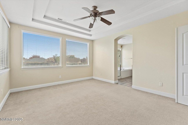 1239 Flintwood Dr, Carson City, NV 89703 - empty room with light colored carpet, a raised ceiling, a ceiling fan, arched walkways, and plenty of natural light