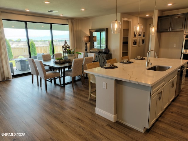2350 Seaberry Dr, Sparks, NV 89441 - kitchen featuring a sink, dark wood-style floors, a kitchen island with sink, hanging light fixtures, and light stone counters