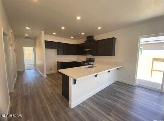877 Agate Way, Fernley, NV 89408 - kitchen with stove, dark wood-style floors, a peninsula, baseboards, and light countertops