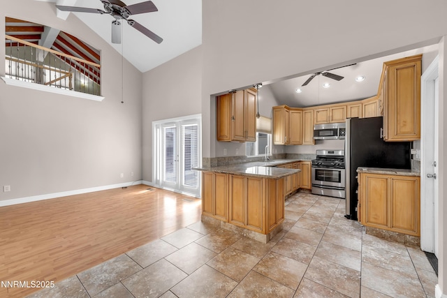 1220 Conway Ln, Reno, NV 89503 - kitchen with a ceiling fan, appliances with stainless steel finishes, high vaulted ceiling, a peninsula, and light stone countertops
