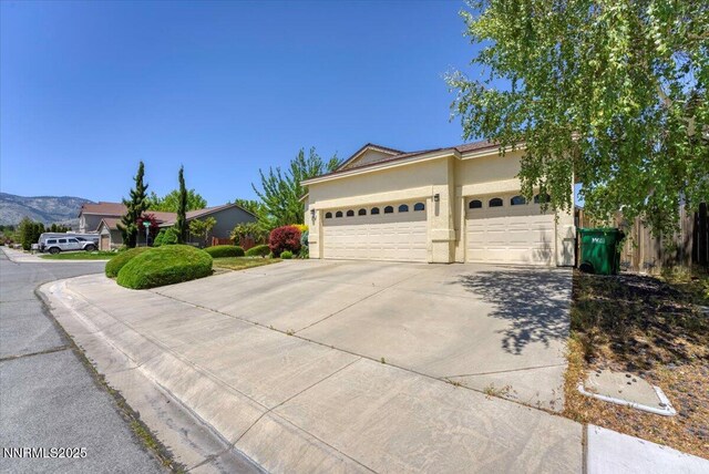 1328 Windridge Dr, Carson City, NV 89706 - view of front of property with concrete driveway, an attached garage, stucco siding, and a mountain view