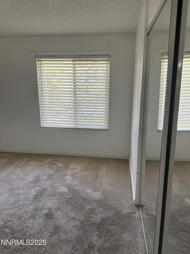 3926 Clear Acre Ln Unit 107, Reno, NV 89512 - unfurnished bedroom with carpet floors, multiple windows, a textured ceiling, a closet, and baseboards