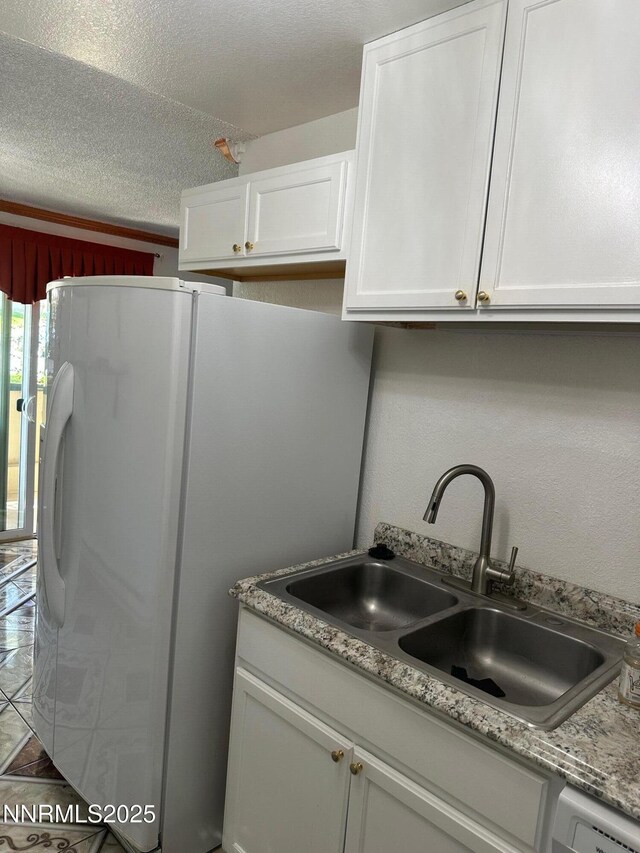 3926 Clear Acre Ln Unit 107, Reno, NV 89512 - kitchen with a sink, freestanding refrigerator, white cabinets, a textured ceiling, and light countertops