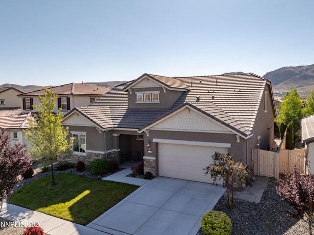 10260 Rollins Dr, Reno, NV 89521 - view of front of home featuring an attached garage, driveway, stone siding, stucco siding, and a tile roof