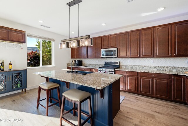 10260 Rollins Dr, Reno, NV 89521 - kitchen featuring stainless steel appliances, light wood finished floors, backsplash, light stone countertops, and a kitchen breakfast bar