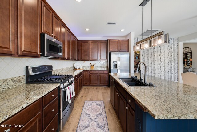 10260 Rollins Dr, Reno, NV 89521 - kitchen featuring stainless steel appliances, a sink, light wood-style floors, backsplash, and light stone counters