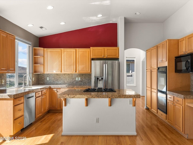 4943 Foxcreek Trl, Reno, NV 89519 - kitchen featuring black appliances, arched walkways, a kitchen island, decorative backsplash, and light wood-style floors
