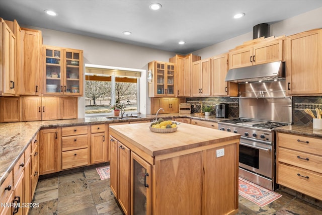 2607 Bowers Rd, Gardnerville, NV 89410 - kitchen with butcher block counters, under cabinet range hood, stainless steel range with gas stovetop, a kitchen island, and decorative backsplash