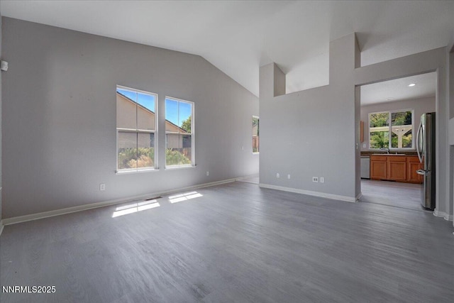 5737 Sonora Pass Dr, Sparks, NV 89436 - unfurnished living room featuring wood finished floors, baseboards, a sink, and high vaulted ceiling