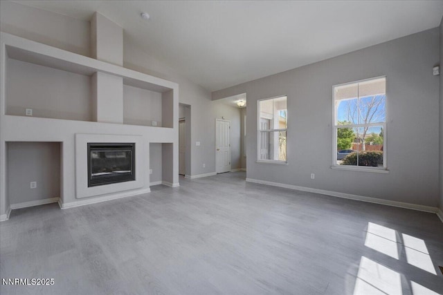 5737 Sonora Pass Dr, Sparks, NV 89436 - unfurnished living room featuring wood finished floors, baseboards, high vaulted ceiling, and a glass covered fireplace