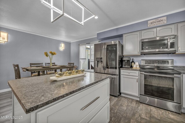 7395 Pah Rah Dr, Sparks, NV 89436 - kitchen with appliances with stainless steel finishes, crown molding, dark wood-style flooring, and a center island