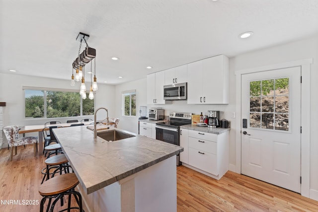 13820 Virginia Foothills Dr, Reno, NV 89521 - kitchen with appliances with stainless steel finishes, a sink, a kitchen breakfast bar, light wood finished floors, and recessed lighting