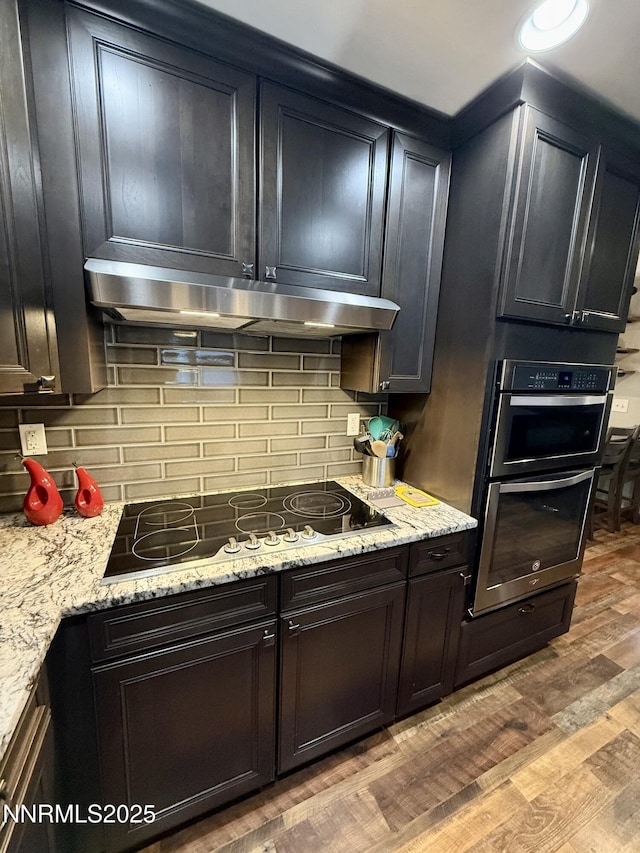 3100 Pine Ln, Carson City, NV 89706 - kitchen featuring black electric stovetop, light wood-style flooring, tasteful backsplash, stainless steel double oven, and under cabinet range hood