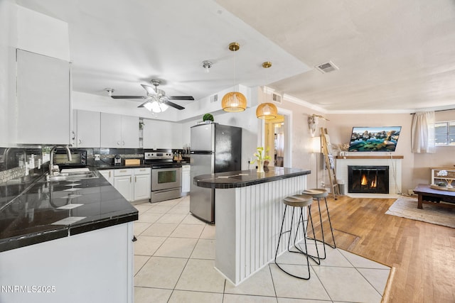 1712 Chaska Pl, Reno, NV 89502 - kitchen featuring stainless steel appliances, a sink, a kitchen bar, ceiling fan, and a tiled fireplace