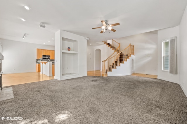 6638 Aston Cir, Sparks, NV 89436 - unfurnished living room featuring light colored carpet, stairway, arched walkways, a ceiling fan, and baseboards
