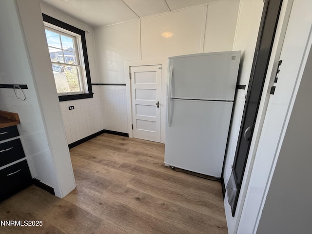 141 University St, Tonopah, NV 89049 - kitchen with freestanding refrigerator, light wood-style flooring, and white cabinets