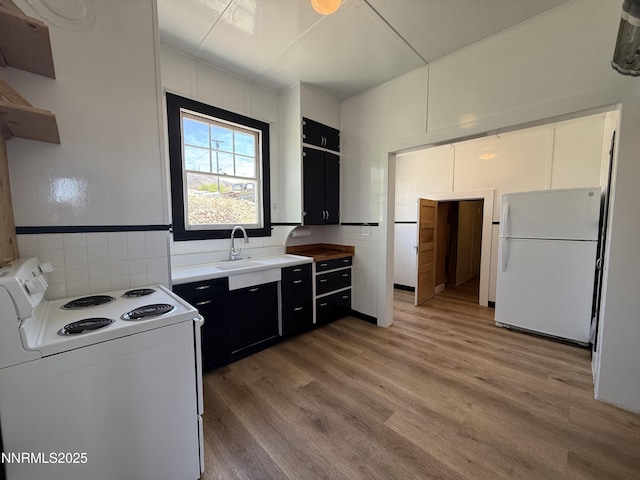 141 University St, Tonopah, NV 89049 - kitchen with white appliances, a sink, dark cabinetry, light wood-type flooring, and tile walls