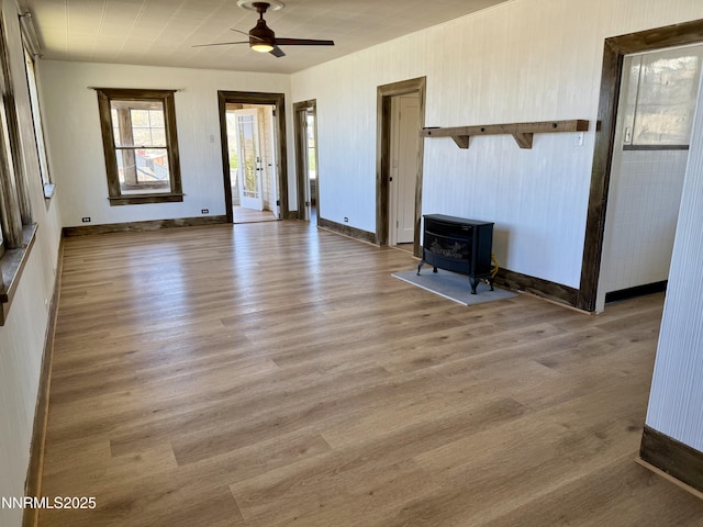 141 University St, Tonopah, NV 89049 - unfurnished living room featuring a wood stove, ceiling fan, wood finished floors, and baseboards