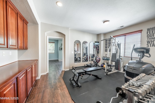 471 Shire Ct, Reno, NV 89521 - exercise area featuring a textured ceiling, arched walkways, dark wood-type flooring, and baseboards