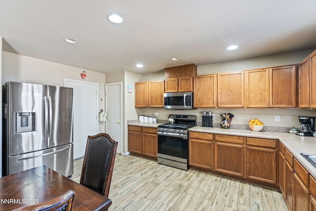 7991 Mariner Cove Dr, Reno, NV 89506 - kitchen featuring appliances with stainless steel finishes, light countertops, light wood-type flooring, brown cabinetry, and recessed lighting