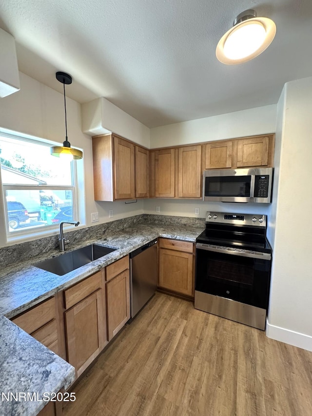 675 E Taylor St, Reno, NV 89502 - kitchen with appliances with stainless steel finishes, a sink, light wood finished floors, stone countertops, and pendant lighting