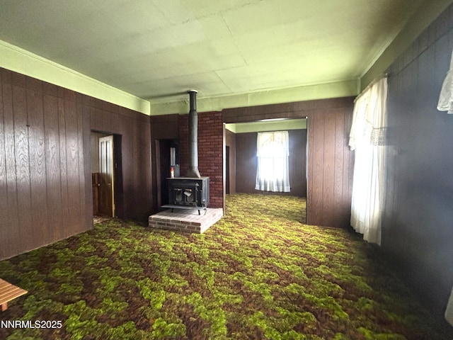 831 N 1st St, Battle Mountain, NV 89820 - unfurnished living room featuring a wood stove, wood walls, and carpet floors
